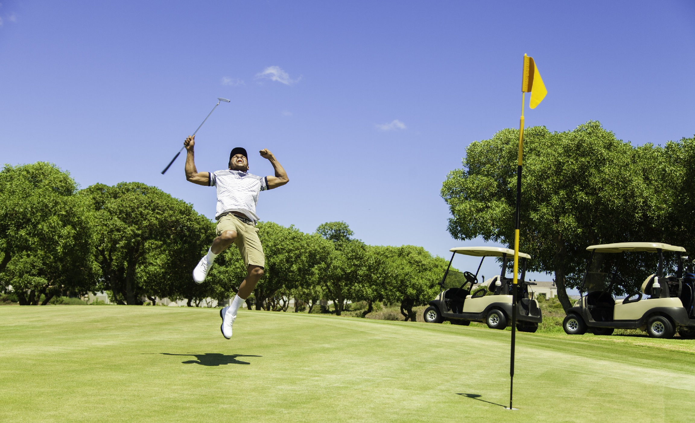 Man jumping in the air in celebration on a golf course